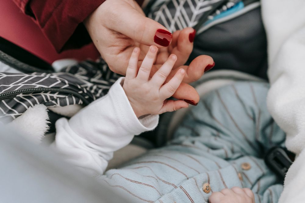 Mother gently holding her newborn baby's hand
